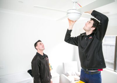 Electricians installing a ceiling fan for summer